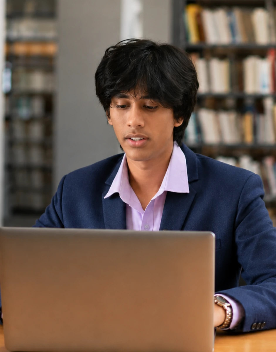 Liberal Arts Ph.D. scholar researching on a laptop in the library